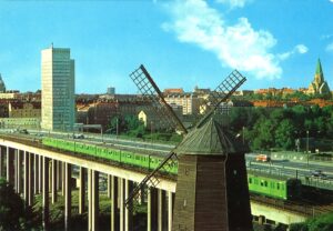 Vykort från det gamla Stockholm, tunnelbanans gröna linje på väg över Skanstullsbron med Folksamhuset i bakgrunden och Skanskvarn i centrum av vykortet